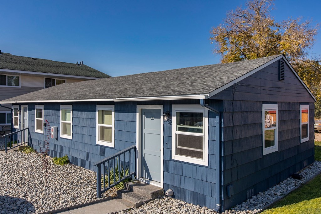 Paved path to the exterior of homes with many windows surrounded by decorative rocks, grass, and landscaping.at The Lakes Apartments, Moses Lake Washington