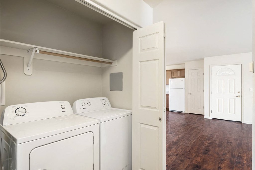 A laundry closet with accordion doors, a white washer and dryer, and shelf storage above. at Pine Tree Park, Washington