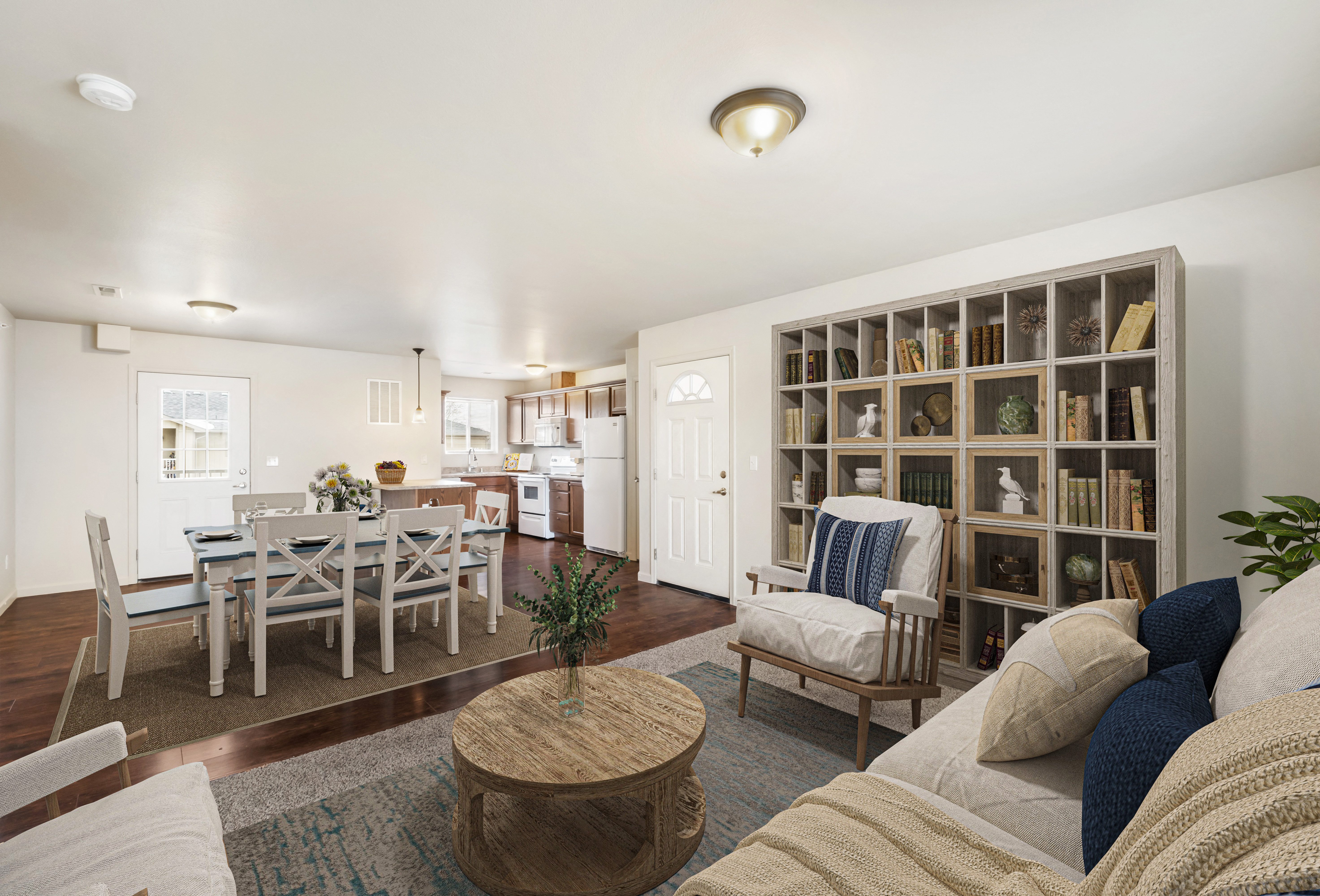 Spacious living room opens into the dining area with a door to the balcony. Staged with couch, coffee table, and 2 chairs. at Pine Tree Park, Kennewick, WA