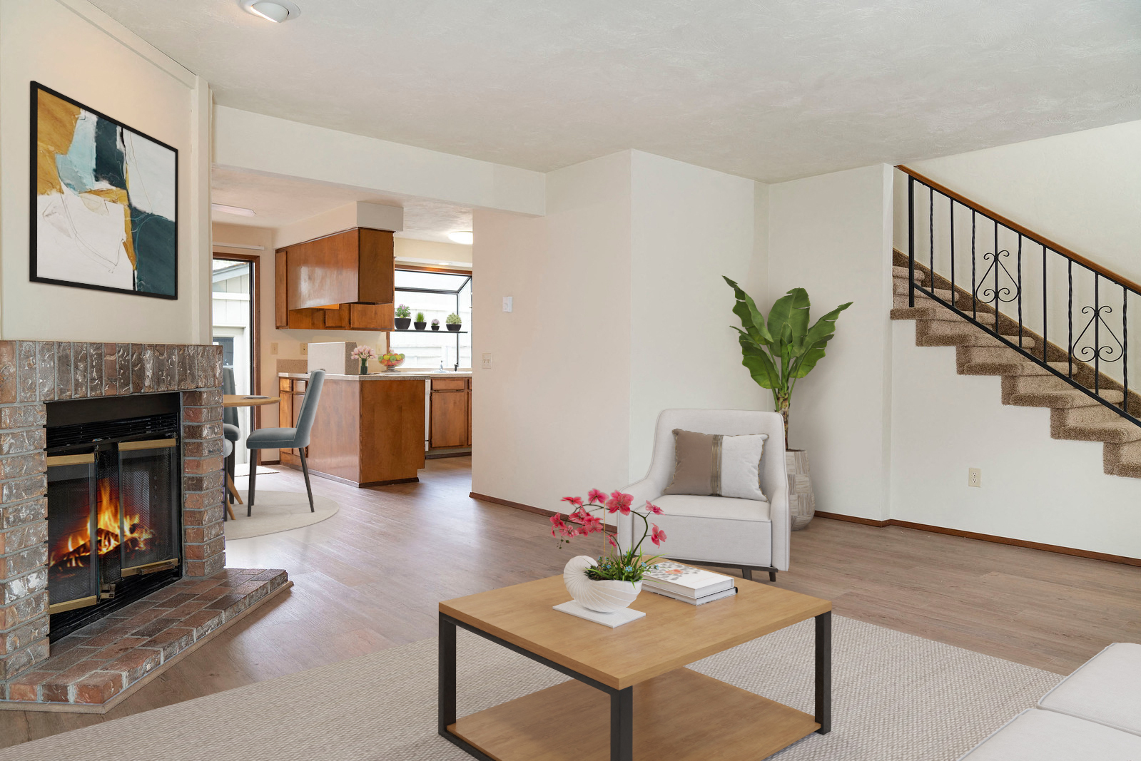 Living room with brick fireplace to the left, opening to the dining and kitchen area, stairs to upstairs on the right.