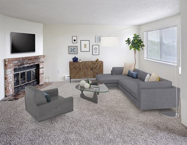 Living room with couch and chair with a coffee table in the middle.  Decorated with a plant, floor lamp, wall art, and a tv above the fireplace.