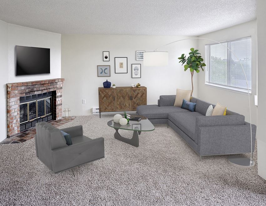 Living room with couch and chair with a coffee table in the middle.  Decorated with a plant, floor lamp, wall art, and a tv above the fireplace. - Photo Gallery 1
