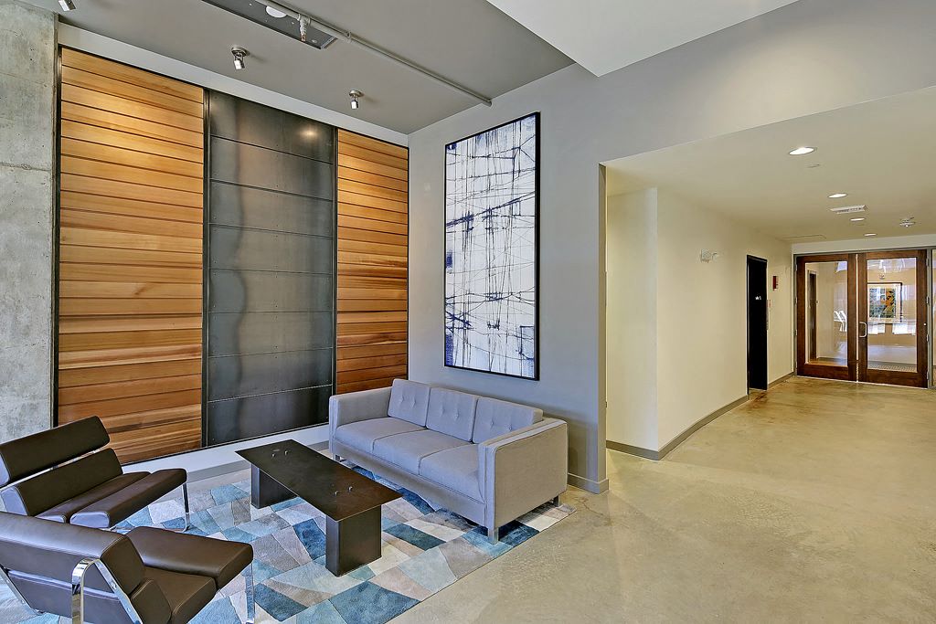 Lobby with laminate flooring, tall ceiling and art. Furnished with couch, 2 chairs and coffee table.at 19th & Mercer, Seattle, WA