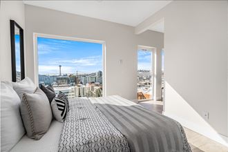Corner home bedroom with windows lined on the far wall leading to the hallway. Space Needle and city view.