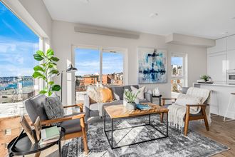Light-filled living room, huge windows, Lake Union, and city views. Staged with 2 chairs, coffee table, couch, side tables.