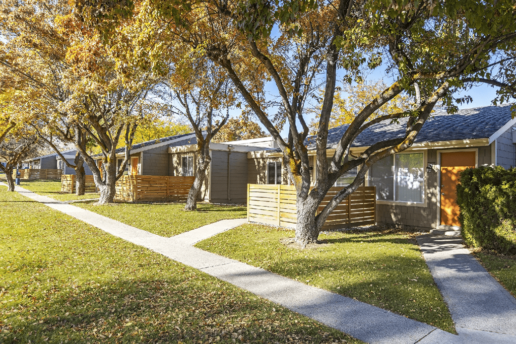 Sidewalks outside units with fenced yards with large trees and grassy areas at Park View Apartments, Washington