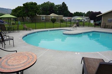 Curved outdoor pool with fence around it.