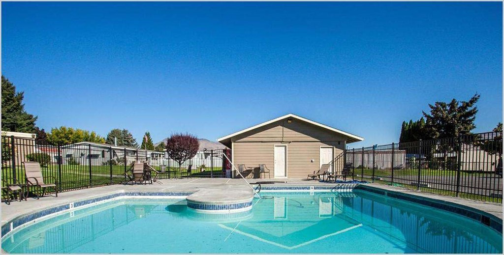 Swimming pool and pool house with lounge chairs and trees in the distance at Park View Apartments, Wenatchee Washington