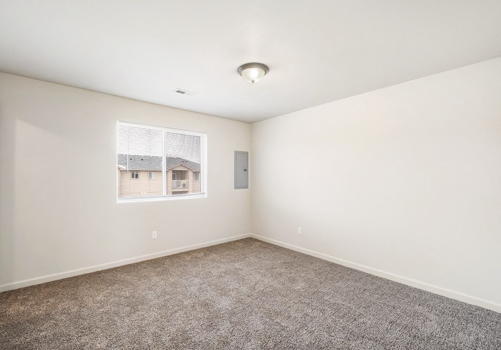 Clean, bright bedroom with taupe carpet, white walls and a large window in one wall. at Pine Tree Park, Washington, 99337