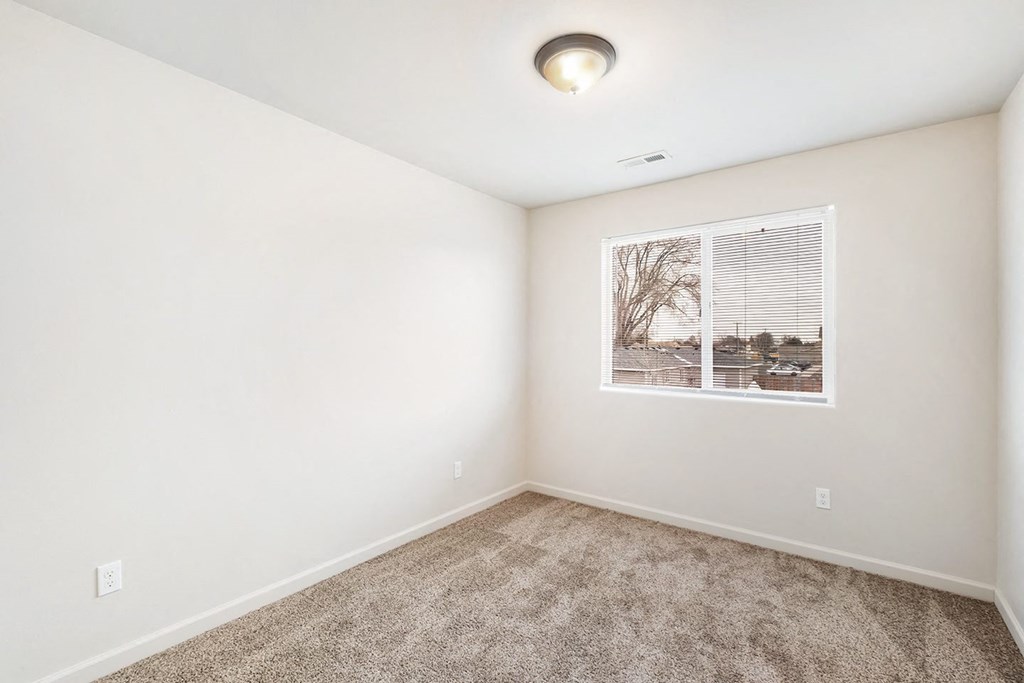 Clean, bright bedroom with taupe carpet, white walls and a large window on one wall. at Pine Tree Park, Washington