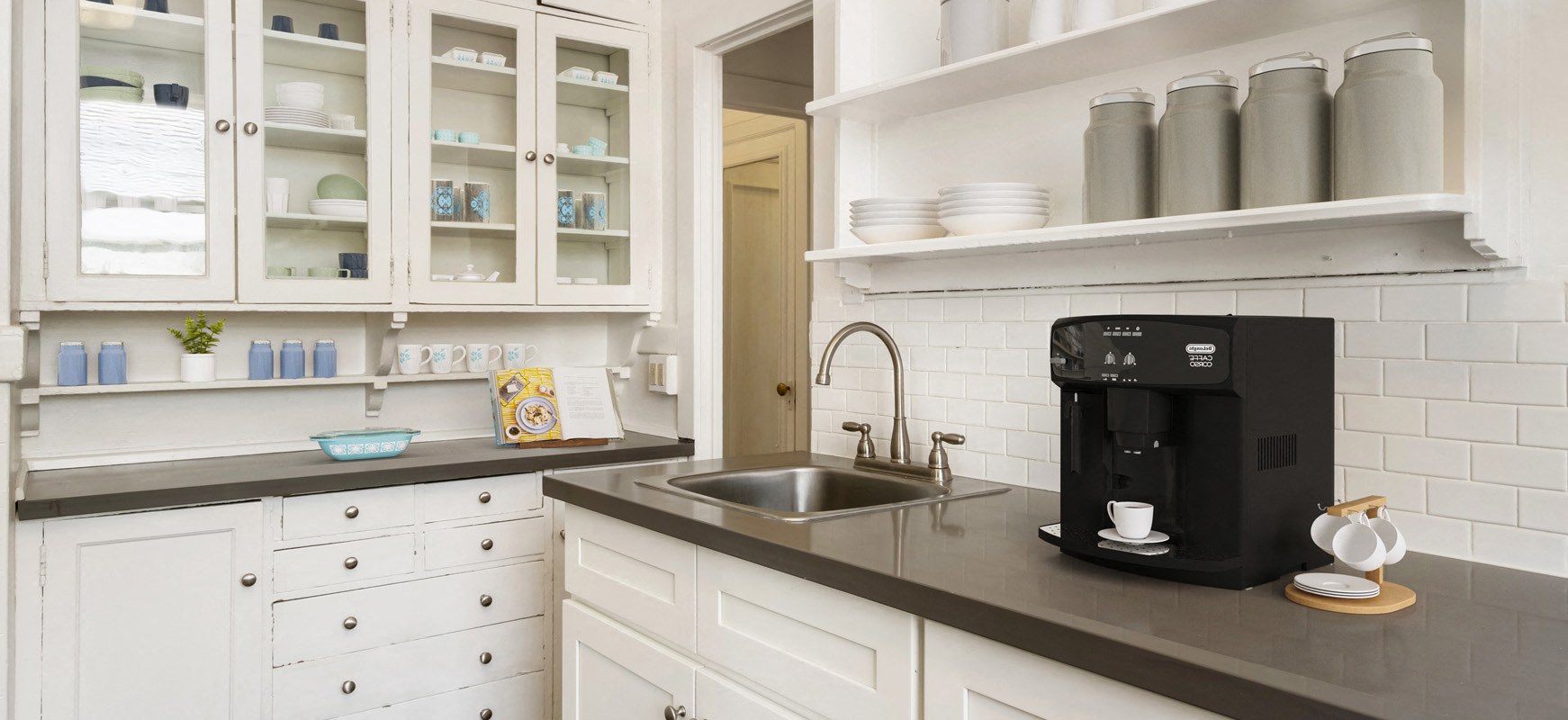 a kitchen with white cabinets and a black counter top