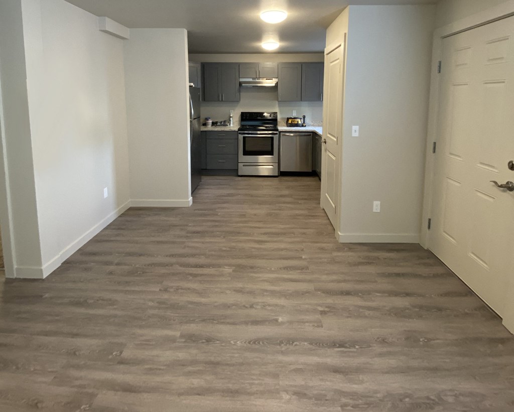 a view of a kitchen and a hallway with wood flooring at The Lakes in Moses Lake, WA.