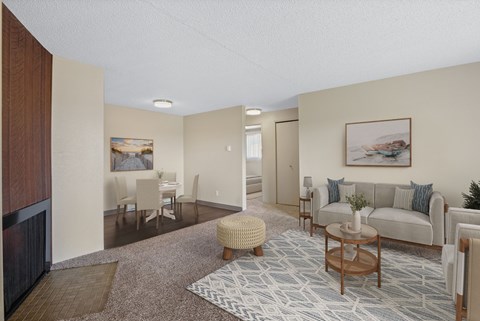 Bright living room with neutral couch, accent chairs, and coffee table in an 850 sq ft 2 bed apartment