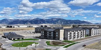 A large apartment complex with a parking lot and a mountain range in the background. at Yellowstone Landing, Montana, 59714