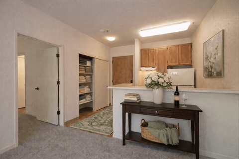 A kitchen area with a table holding a vase of flowers and a bottle of wine.