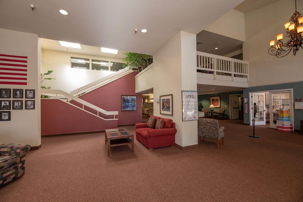 a living room with a red couch and a staircase at Hilltop Commons Senior Living, California