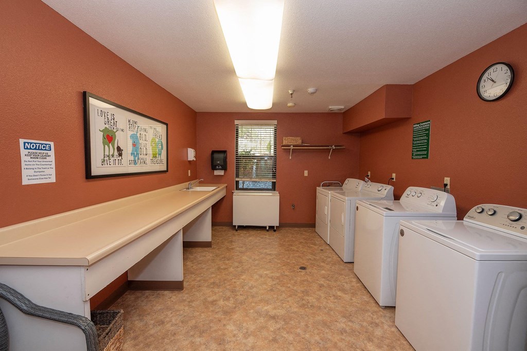 a washer and dryer room with a row of washing machines at Hilltop Commons Senior Living, Grass Valley, 95945