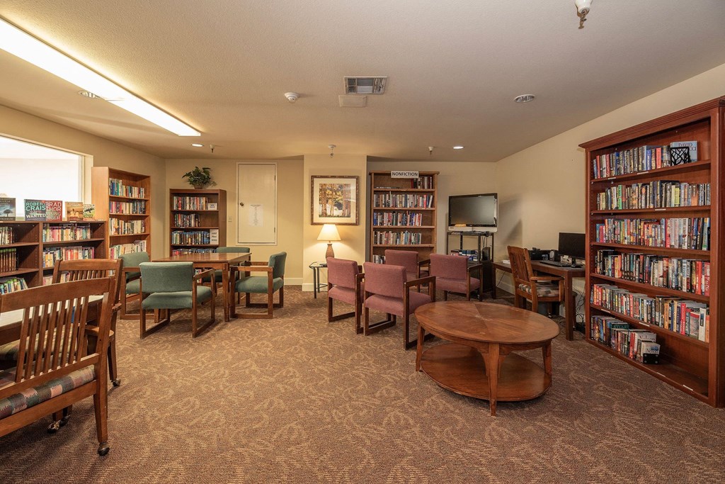 a library with tables and chairs and shelves of books at Hilltop Commons Senior Living, Grass Valley, CA