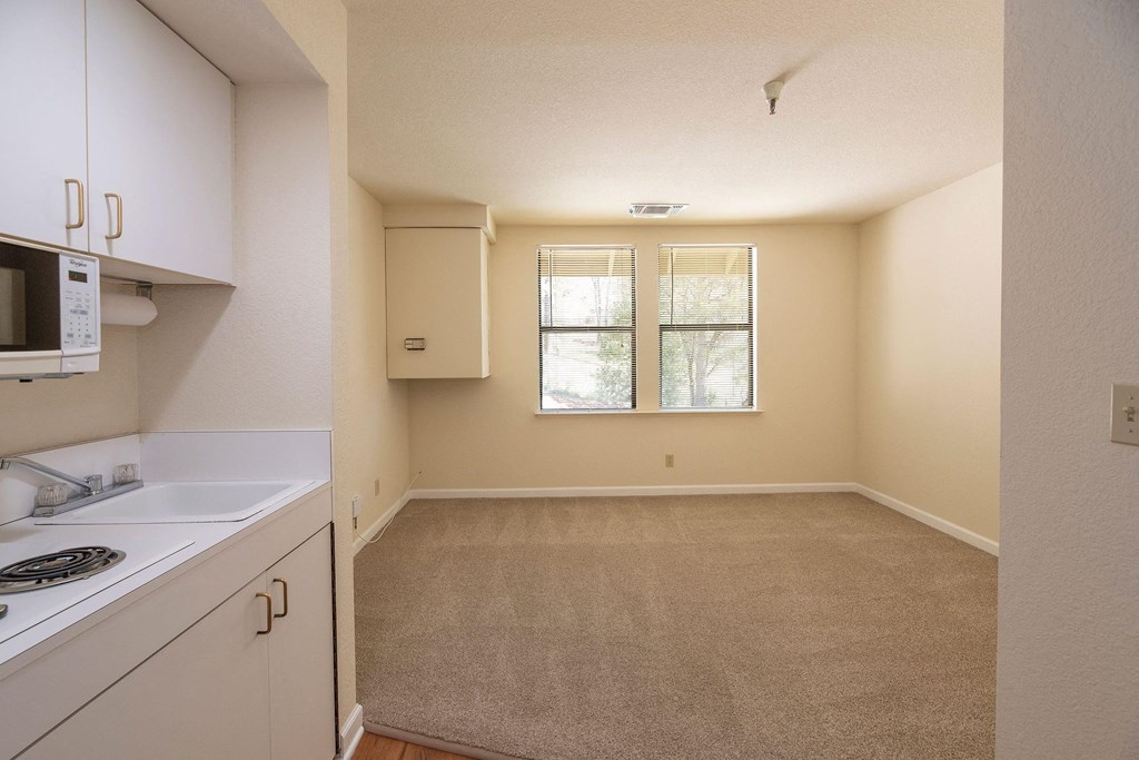 an empty kitchen with white cabinets and a window at Hilltop Commons Senior Living, Grass Valley California