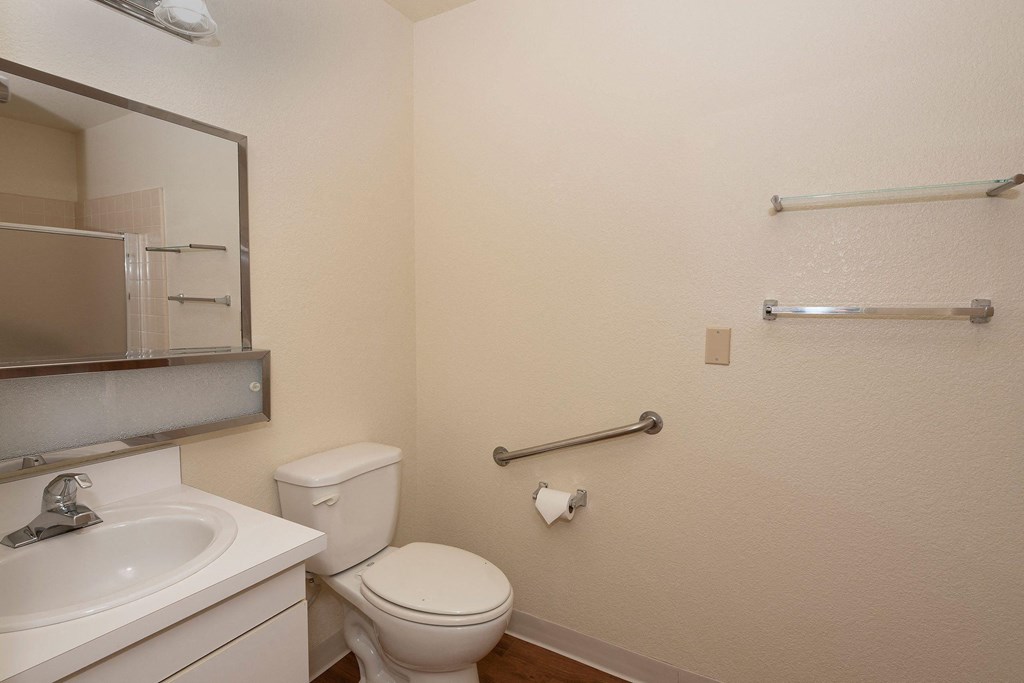 a bathroom with a toilet and a sink and a mirror at Hilltop Commons Senior Living, Grass Valley