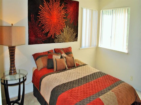 A bedroom with a bed, a lamp, and a painting on the wall.