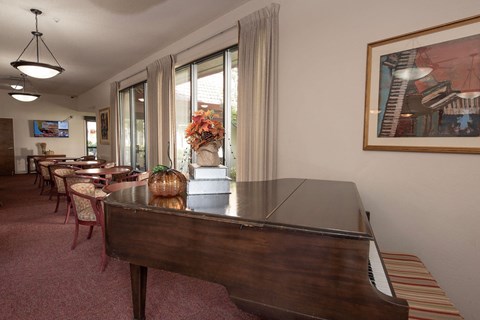 a living room with a piano and a dining room with tables and chairs