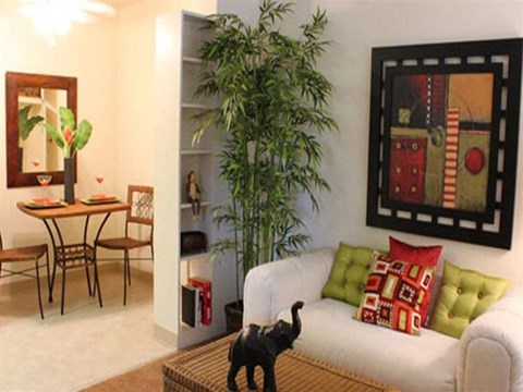 A black cat standing on a wicker basket in a living room.
