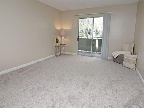 A bedroom with a bed, a nightstand, and a window with a view of trees.