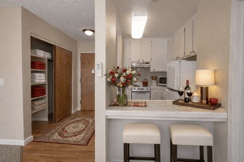 A kitchen with a bar stool and a counter with a vase of flowers on it.