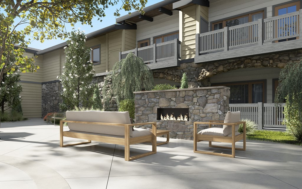 a patio with a stone fireplace and two chairs