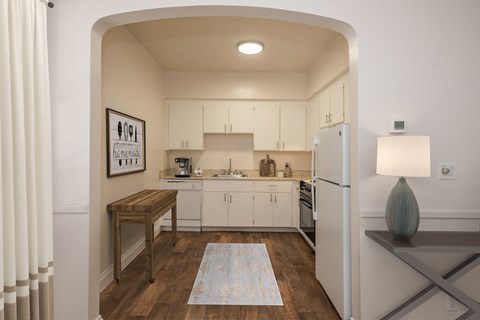 A kitchen with white cabinets and a white fridge.