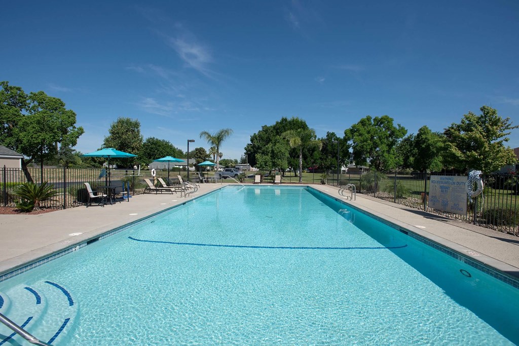 a swimming pool with trees in the background and a blue sky at Castle Vista Senior Duplex Community, Atwater, 95301