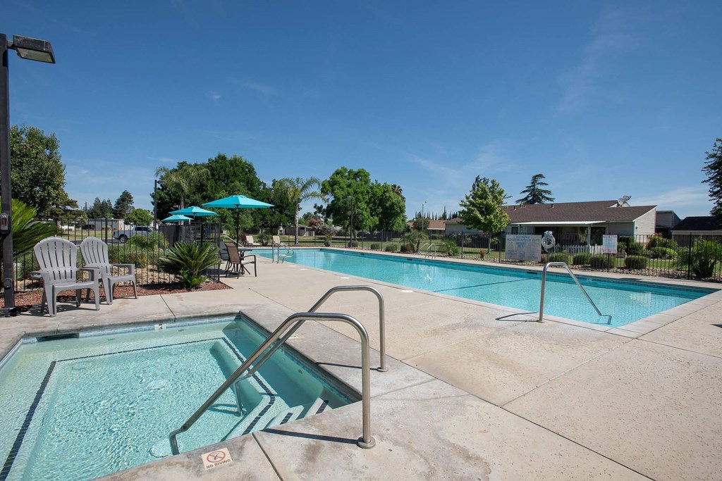 our apartments have a swimming pool with chairs and umbrellas at Castle Vista Senior Duplex Community, Atwater, CA