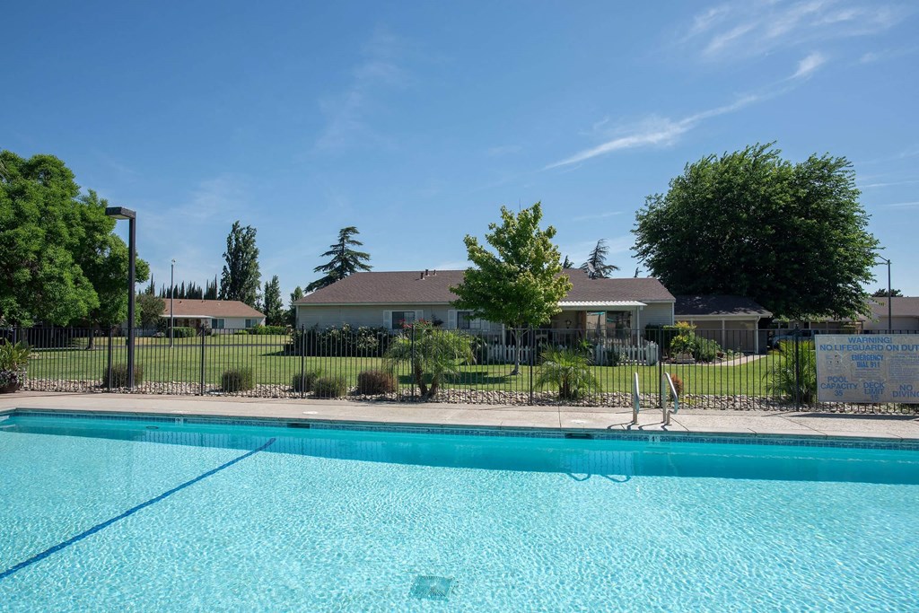a swimming pool with a house in the background at Castle Vista Senior Duplex Community, Atwater, CA, 95301
