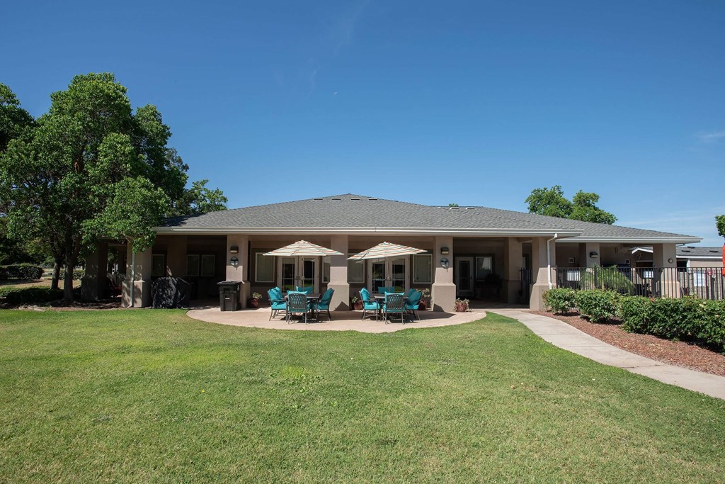 the backyard of a house with patio chairs and umbrellas at Castle Vista Senior Duplex Community, Atwater, CA