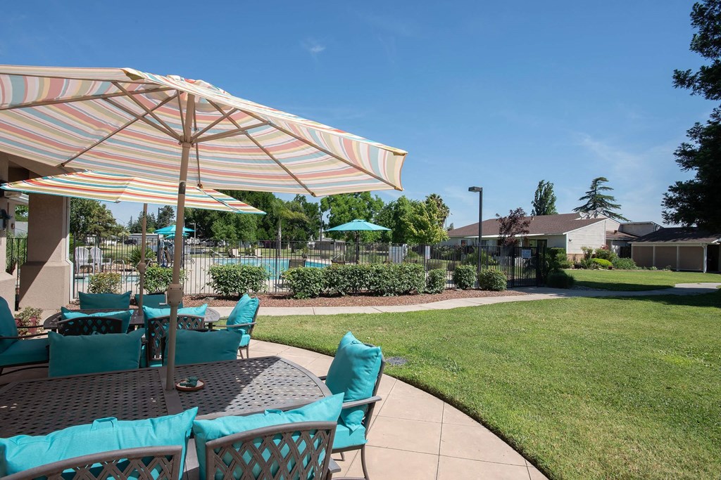 a patio with a table with chairs and an umbrella at Castle Vista Senior Duplex Community, Atwater, California