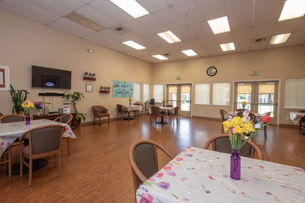 a large room with tables and chairs and a tv at Castle Vista Senior Duplex Community, Atwater, CA, 95301