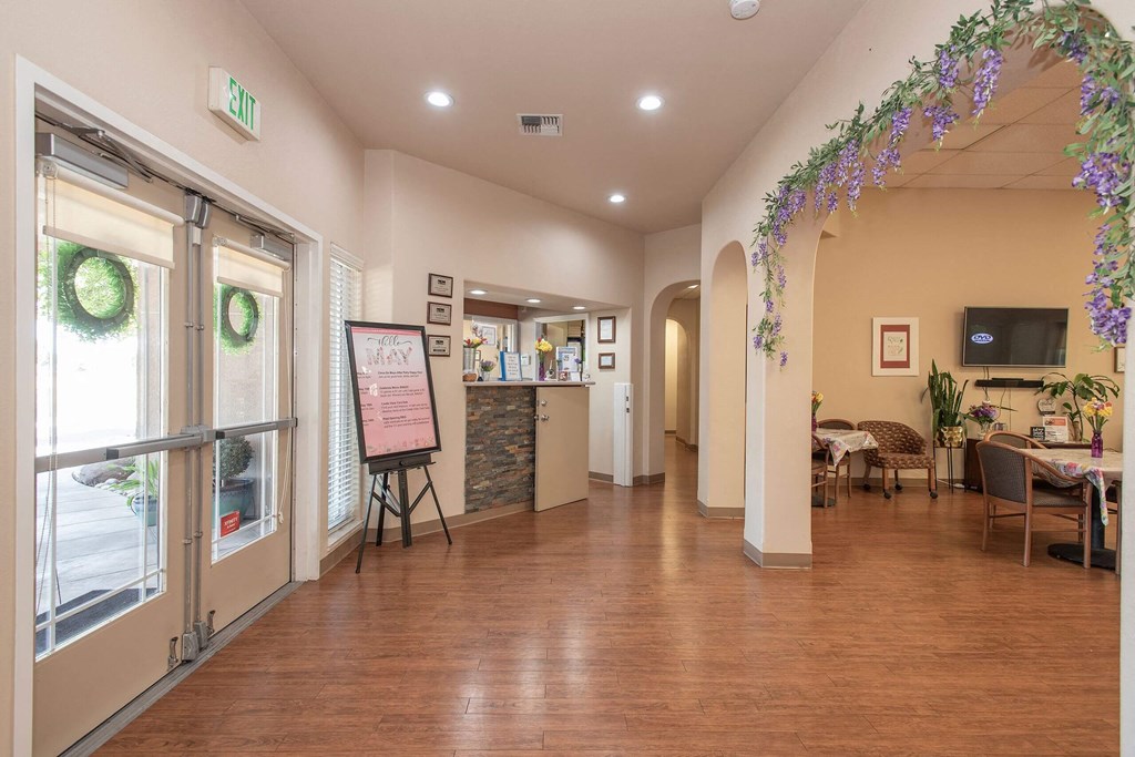 a long hallway with tables and chairs and a bulletin board on the wall at Castle Vista Senior Duplex Community, Atwater
