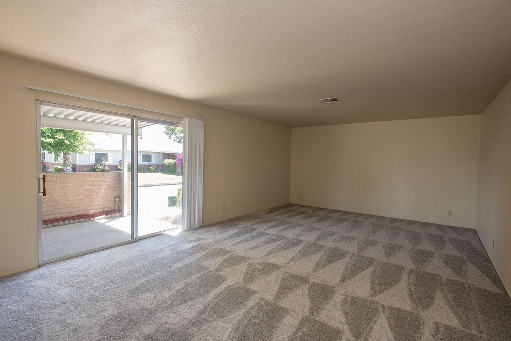an empty living room with sliding glass doors to a patio at Castle Vista Senior Duplex Community, Atwater