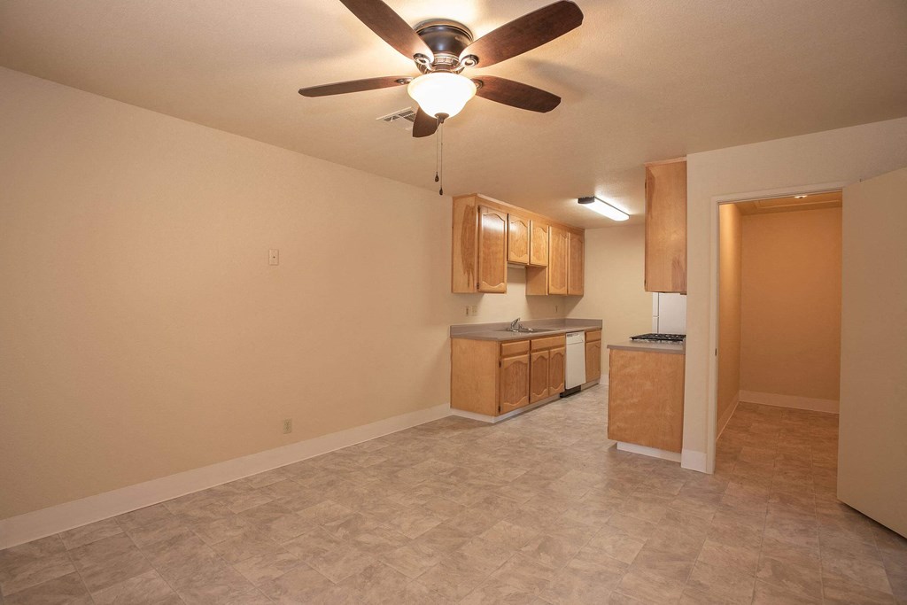 an empty living room with a ceiling fan and a kitchen at Castle Vista Senior Duplex Community, Atwater, California