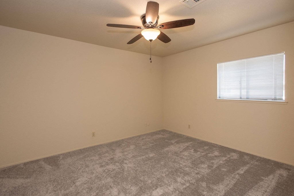 an empty living room with a ceiling fan and a window at Castle Vista Senior Duplex Community, Atwater, CA