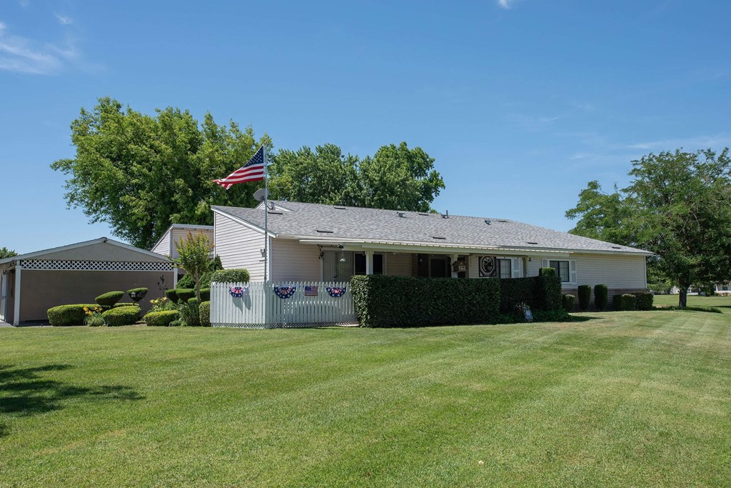a white house with an flag flying in front of it at Castle Vista Senior Duplex Community, Atwater