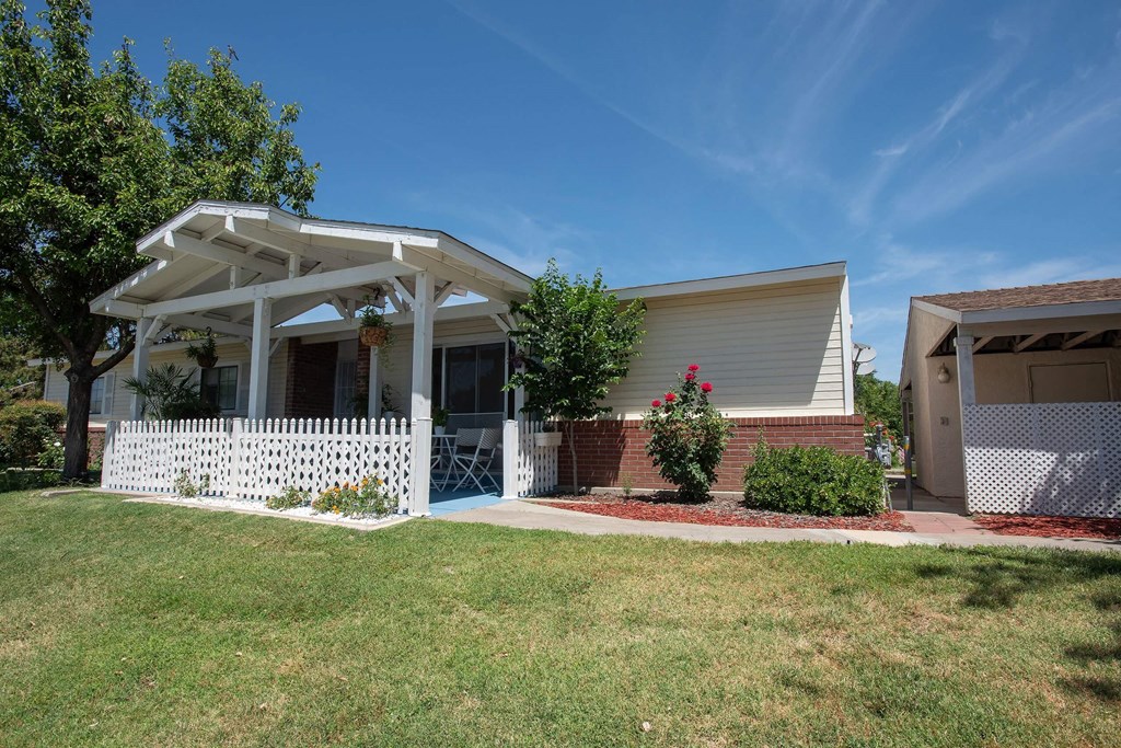 a white house with a lawn and a white picket fence at Castle Vista Senior Duplex Community, Atwater, California