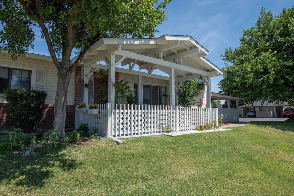 a house with a white porch and a white picket fence at Castle Vista Senior Duplex Community, Atwater, 95301