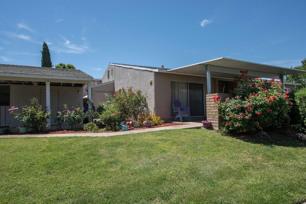 a view of the front of a house with a lawn and flowers at Castle Vista Senior Duplex Community, Atwater, CA