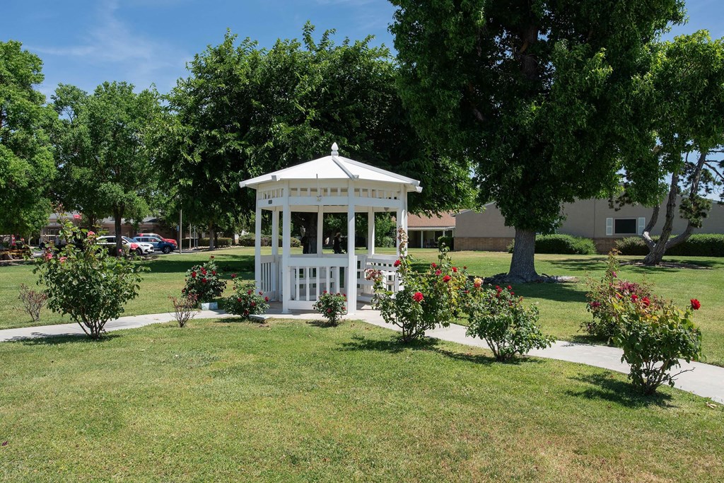a white gazebo in the middle of a park with trees and flowers at Castle Vista Senior Duplex Community, Atwater, CA, 95301