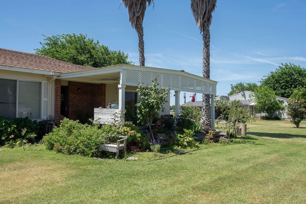 a house with a covered porch and a lawn and palm trees at Castle Vista Senior Duplex Community, Atwater, CA