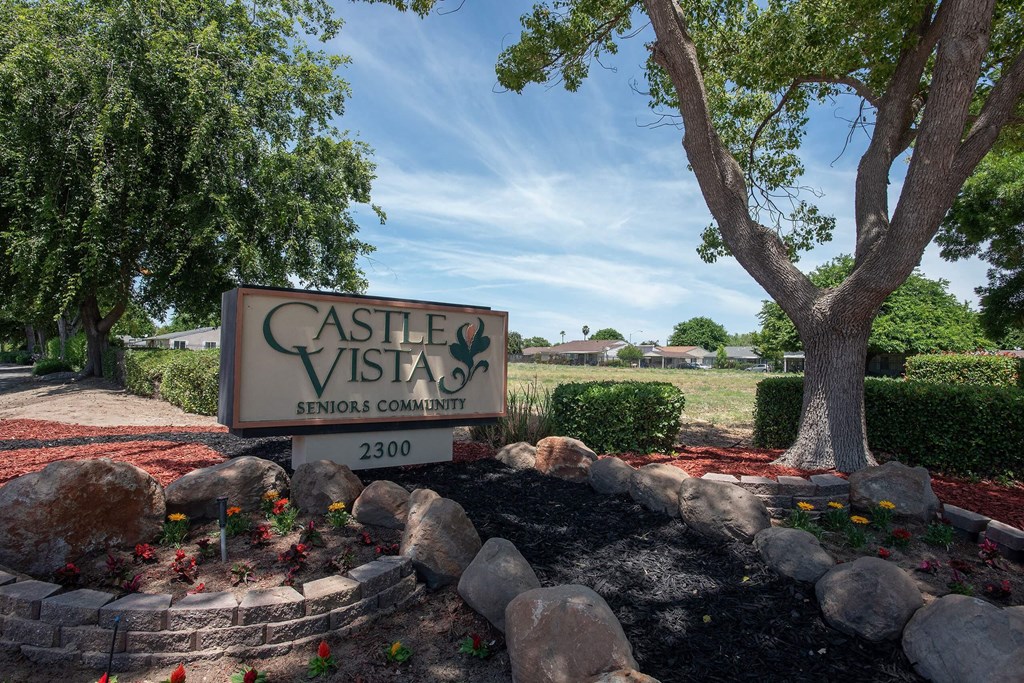 a sign in front of a tree and rocks at Castle Vista Senior Duplex Community, Atwater, California
