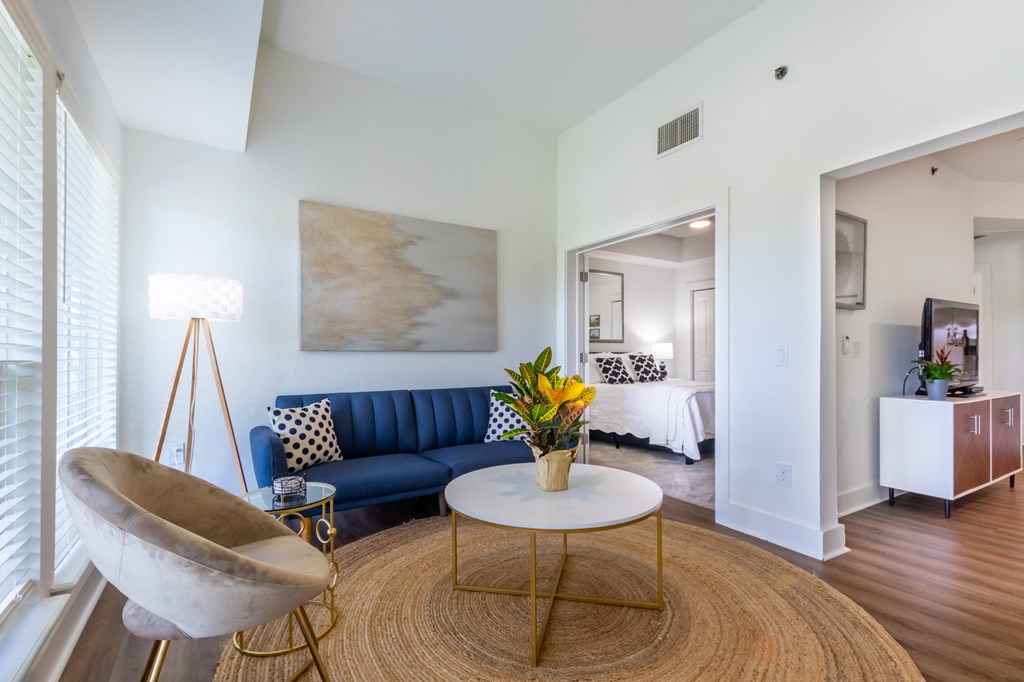 A living room with a blue couch and a gold coffee table.