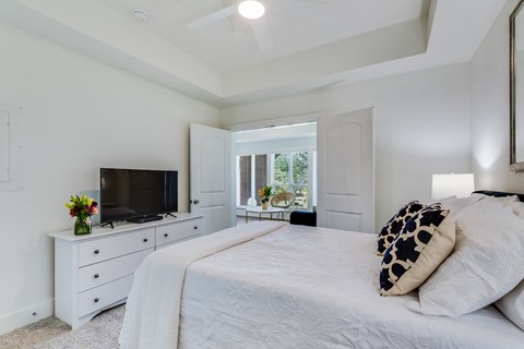 A bedroom with a bed, dresser, and television.